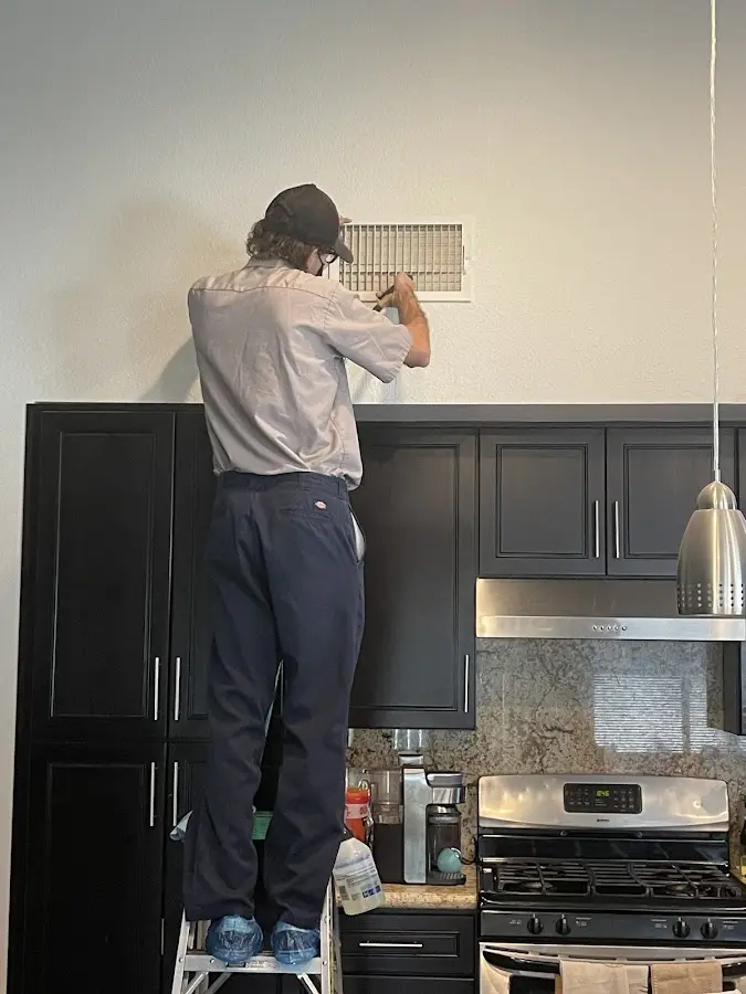 Technician inspecting an air vent during HVAC service in Oak Park